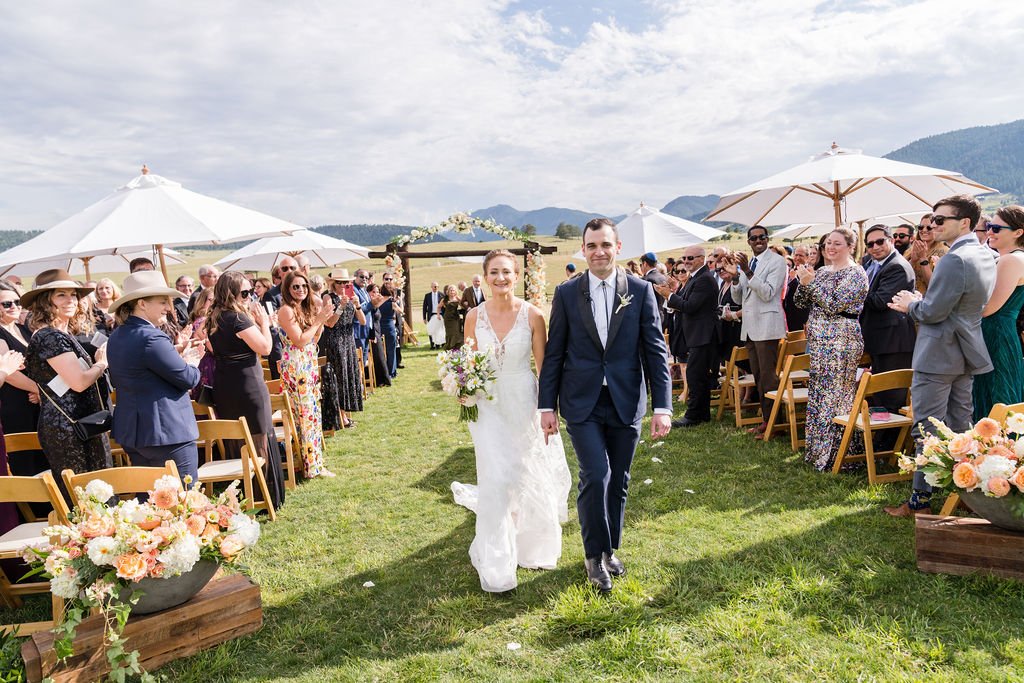 An outdoor ceremony recessional beneath market umbrellas