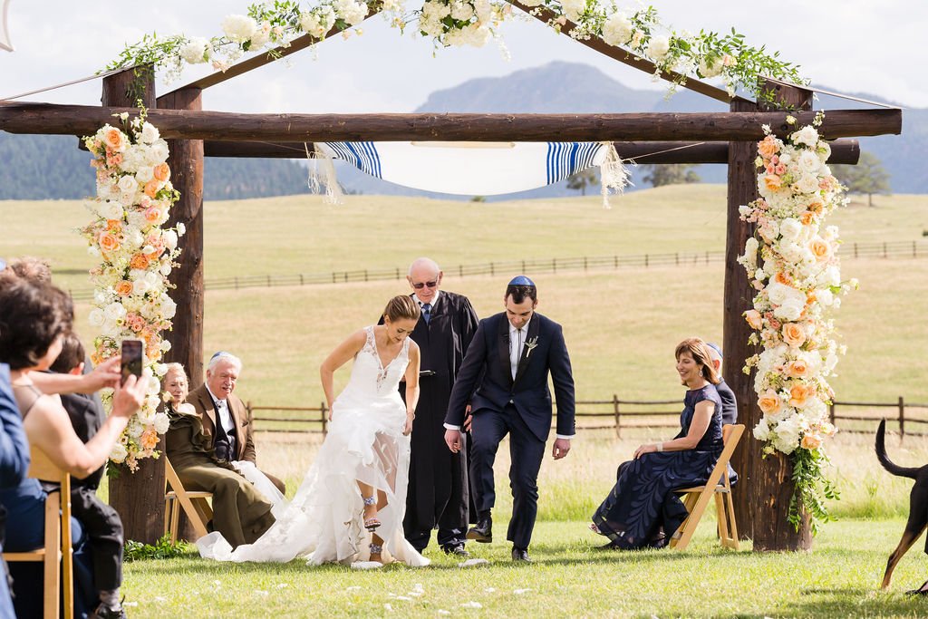 Newlyweds beside a wooden arbor in a mountain meadow