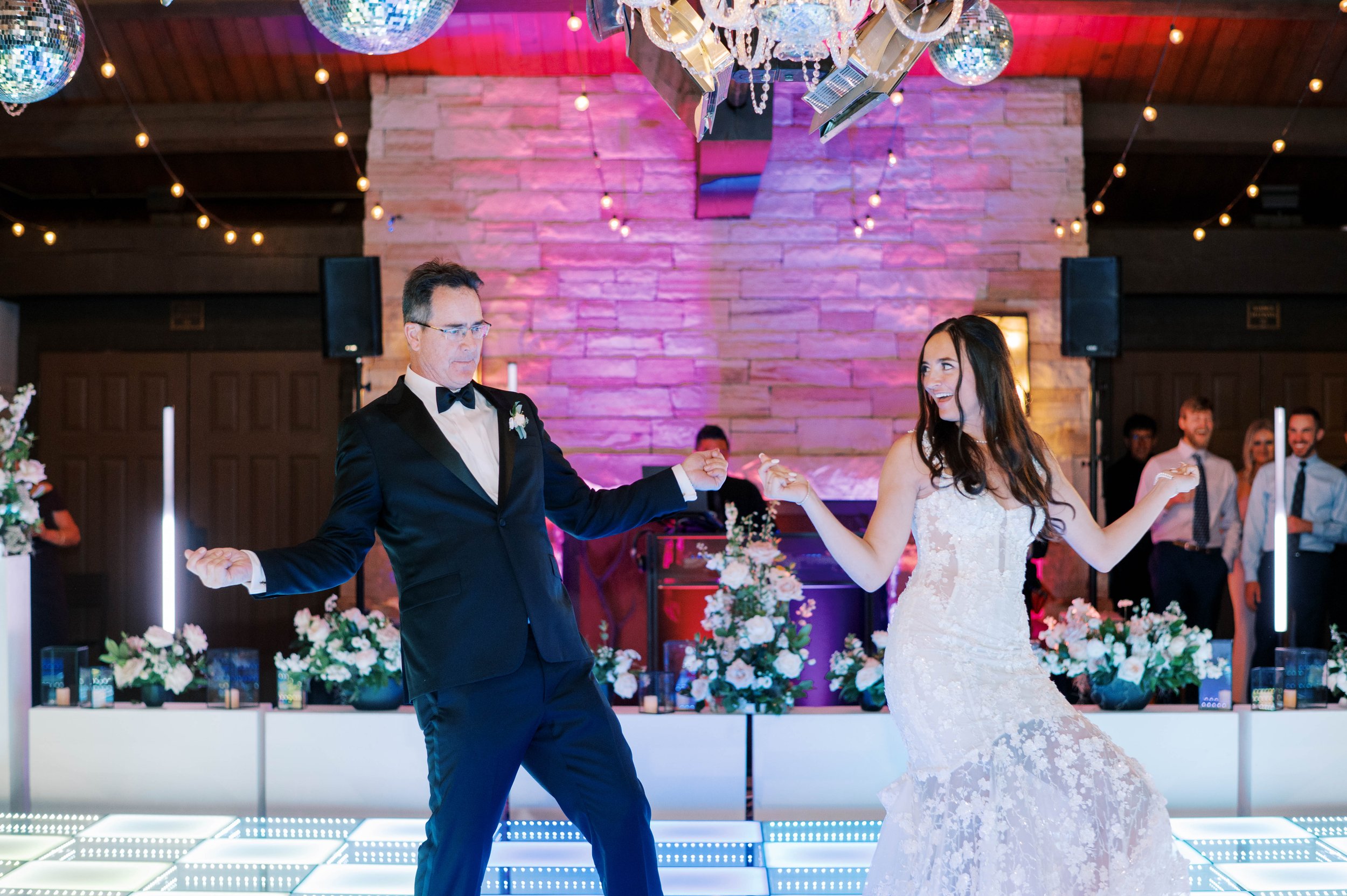 A couple's first dance under warm uplighting