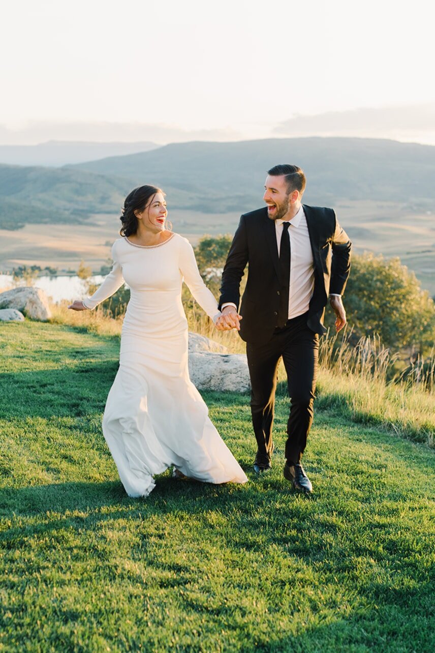 A couple walking a Colorado meadow on their wedding day