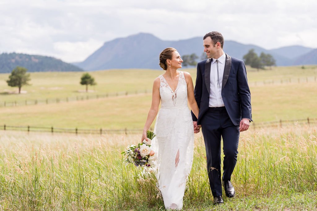 A couple strolling through a golden mountain field